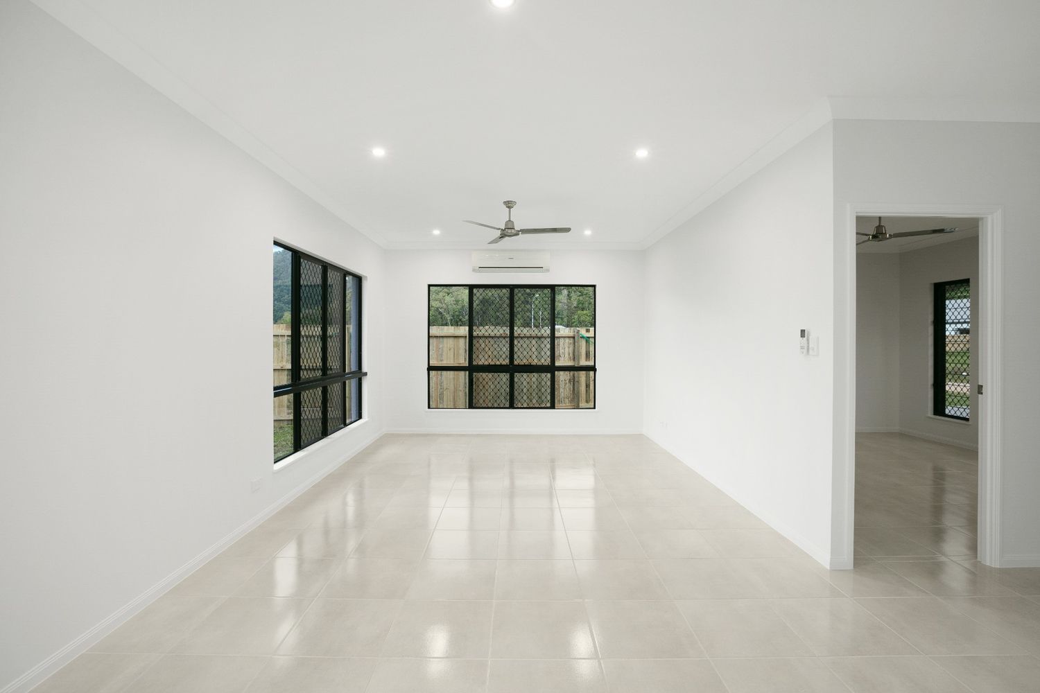 An Empty Living Room With White Walls and a Ceiling Fan — Ashlee Jones Homes in Gordonvale, QLD
