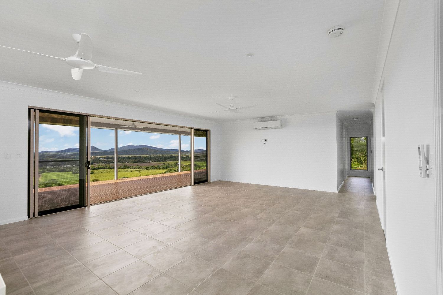 An Empty Living Room With Sliding Glass Doors and a Ceiling Fan — Ashlee Jones Homes in Gordonvale, QLD