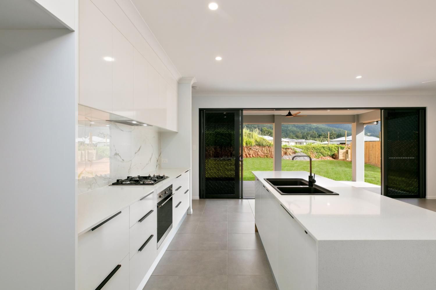 A Kitchen With White Cabinets and Black Handles and a Large Island — Ashlee Jones Homes in Gordonvale, QLD