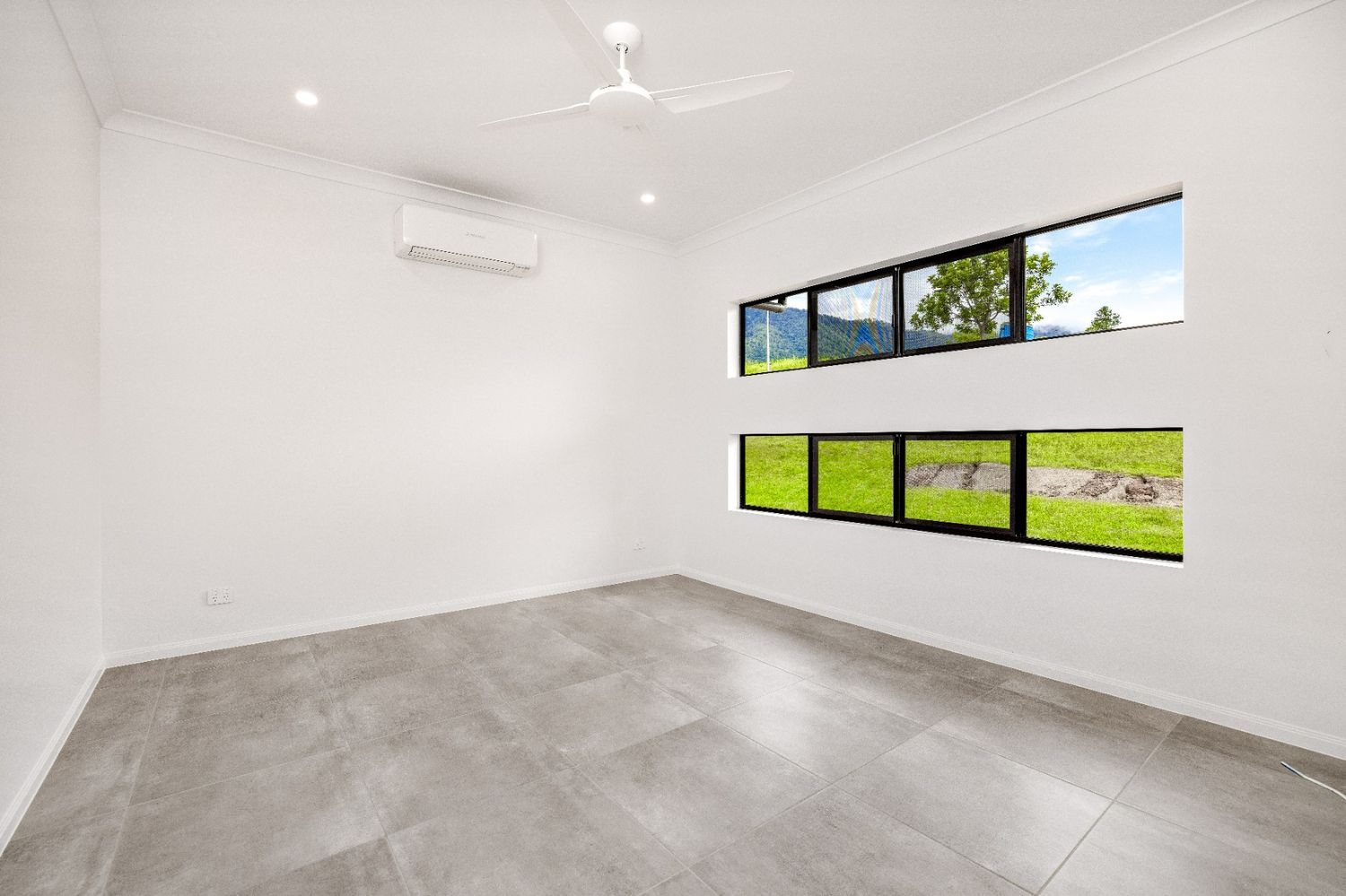 An Empty Room With Two Windows and a Ceiling Fan — Ashlee Jones Homes in Gordonvale, QLD