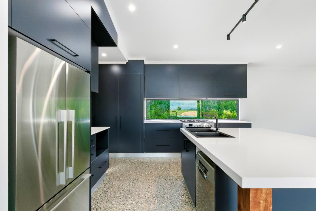 A Kitchen With Stainless Steel Appliances and a Large Island — Ashlee Jones Homes in Gordonvale, QLD