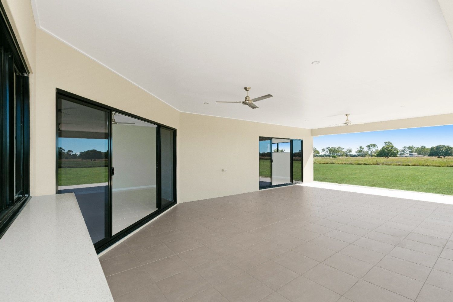 An Empty Room With Sliding Glass Doors and a Ceiling Fan — Ashlee Jones Homes in Gordonvale, QLD