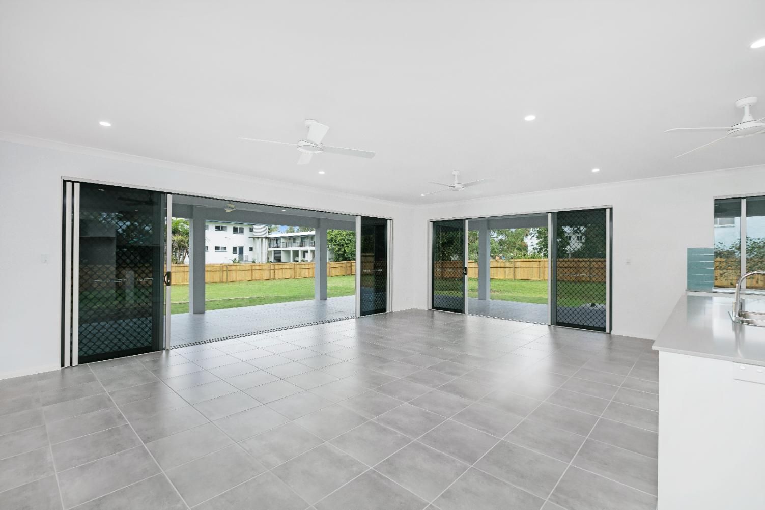 An Empty Living Room With Sliding Glass Doors and a Ceiling Fan — Ashlee Jones Homes in Gordonvale, QLD