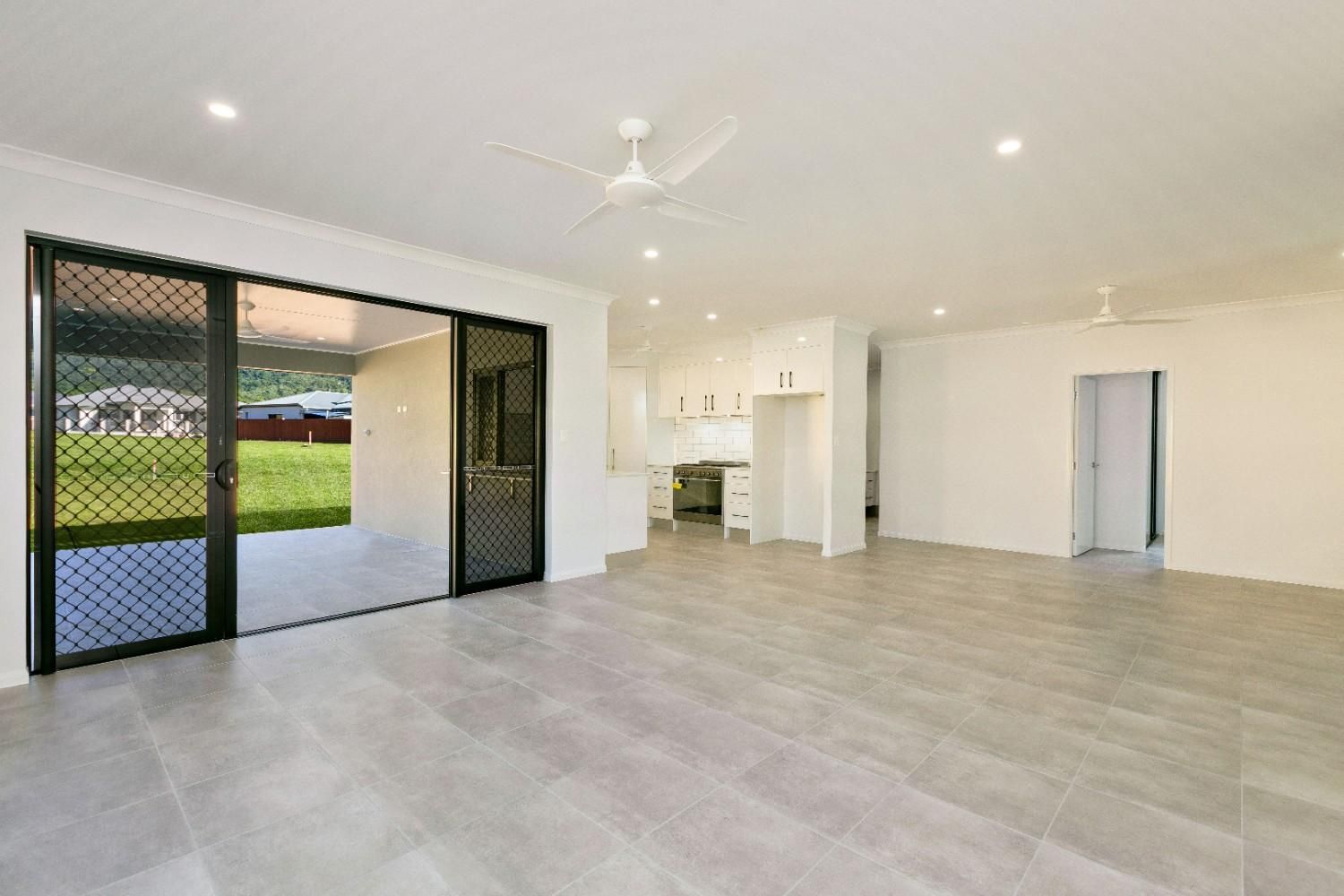 An Empty Living Room With Sliding Glass Doors and a Ceiling Fan  — Ashlee Jones Homes in Gordonvale, QLD