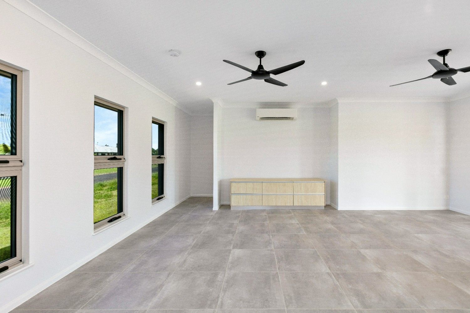 An Empty Living Room With a Ceiling Fan and Three Windows — Ashlee Jones Homes in Gordonvale, QLD