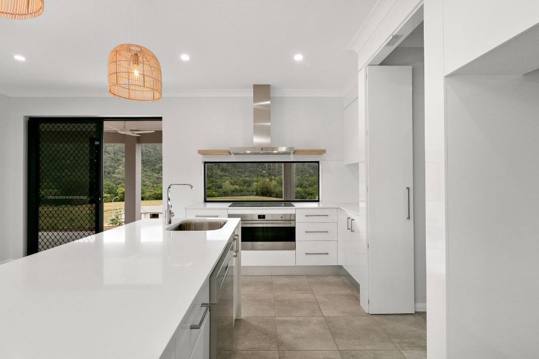 A Kitchen With White Cabinets and Stainless Steel Appliances — Ashlee Jones Homes in Gordonvale, QLD
