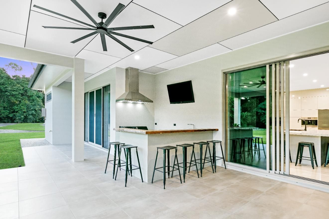 A Patio With Stools and a Ceiling Fan — Ashlee Jones Homes in Gordonvale, QLD