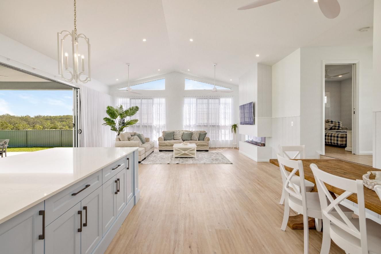 A Living Room With a Couch , Table and Chairs in a House — Ashlee Jones Homes in Gordonvale, QLD