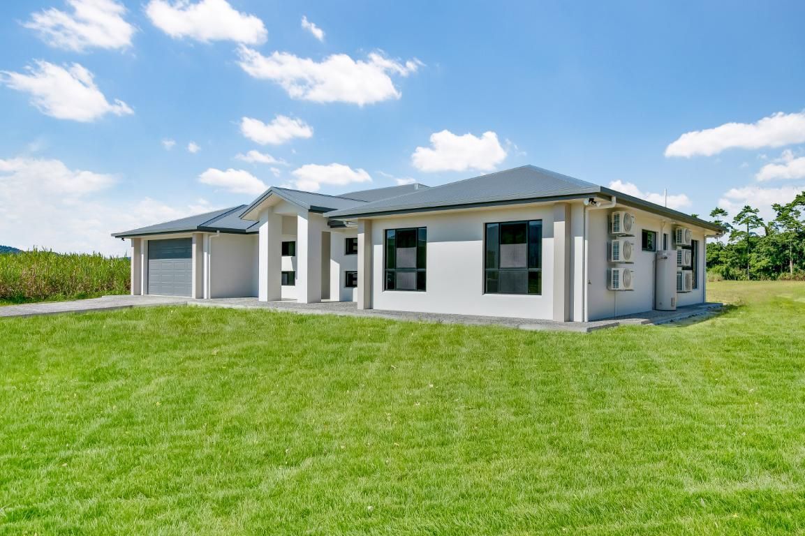 A Large White House is Sitting on Top of a Lush Green Field — Ashlee Jones Homes in Gordonvale, QLD