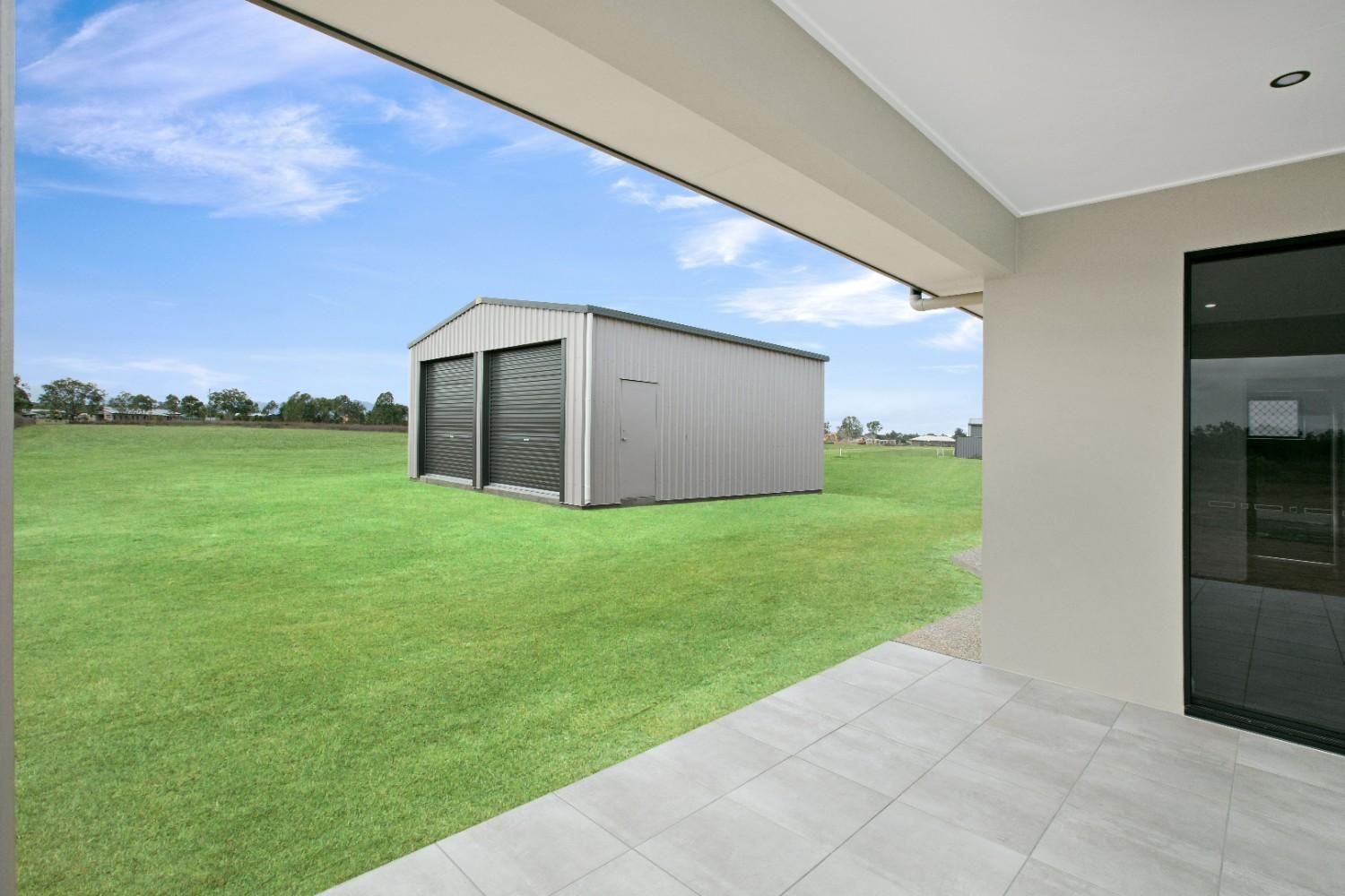 A Shed is Sitting in the Middle of a Lush Green Field — Ashlee Jones Homes in Gordonvale, QLD