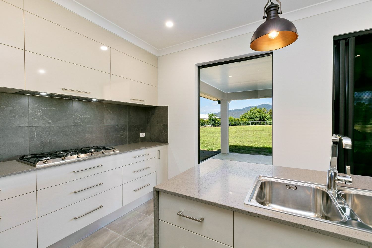 A Kitchen With White Cabinets, a Sink, a Stove and a Window — Ashlee Jones Homes in Gordonvale, QLD