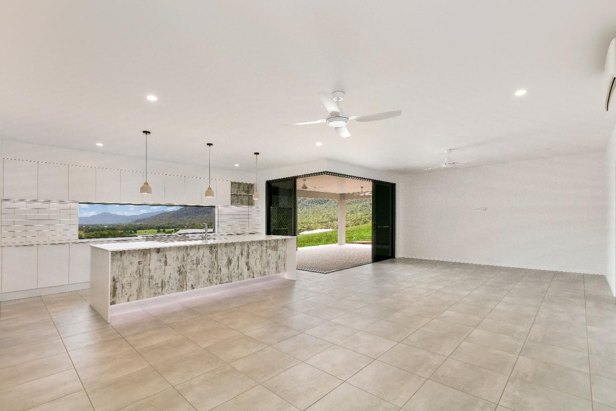 A Large Empty Room With a Kitchen and a Ceiling Fan — Ashlee Jones Homes in Gordonvale, QLD