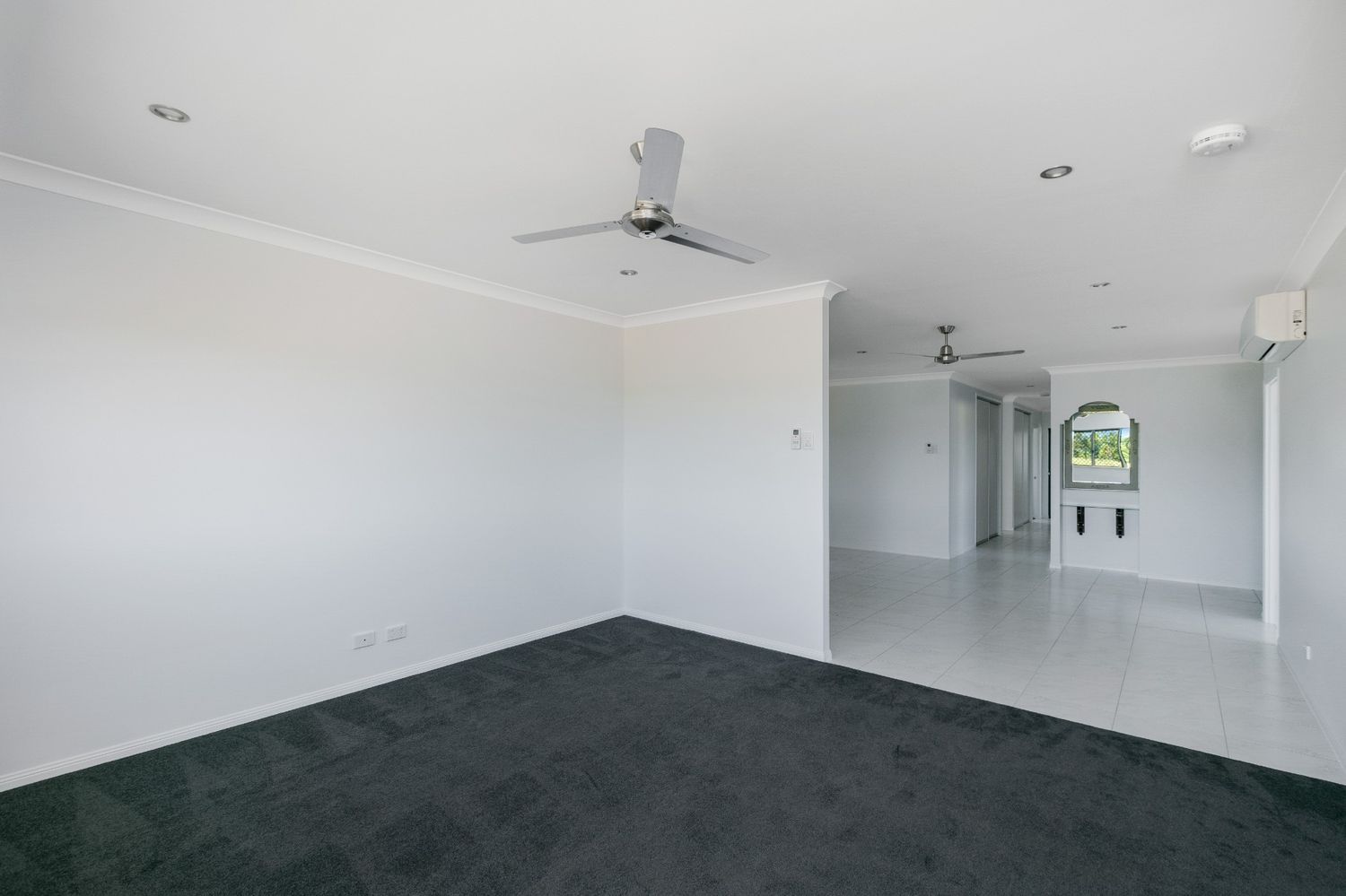 An Empty Living Room With a Ceiling Fan and Black Carpet — Ashlee Jones Homes in Gordonvale, QLD