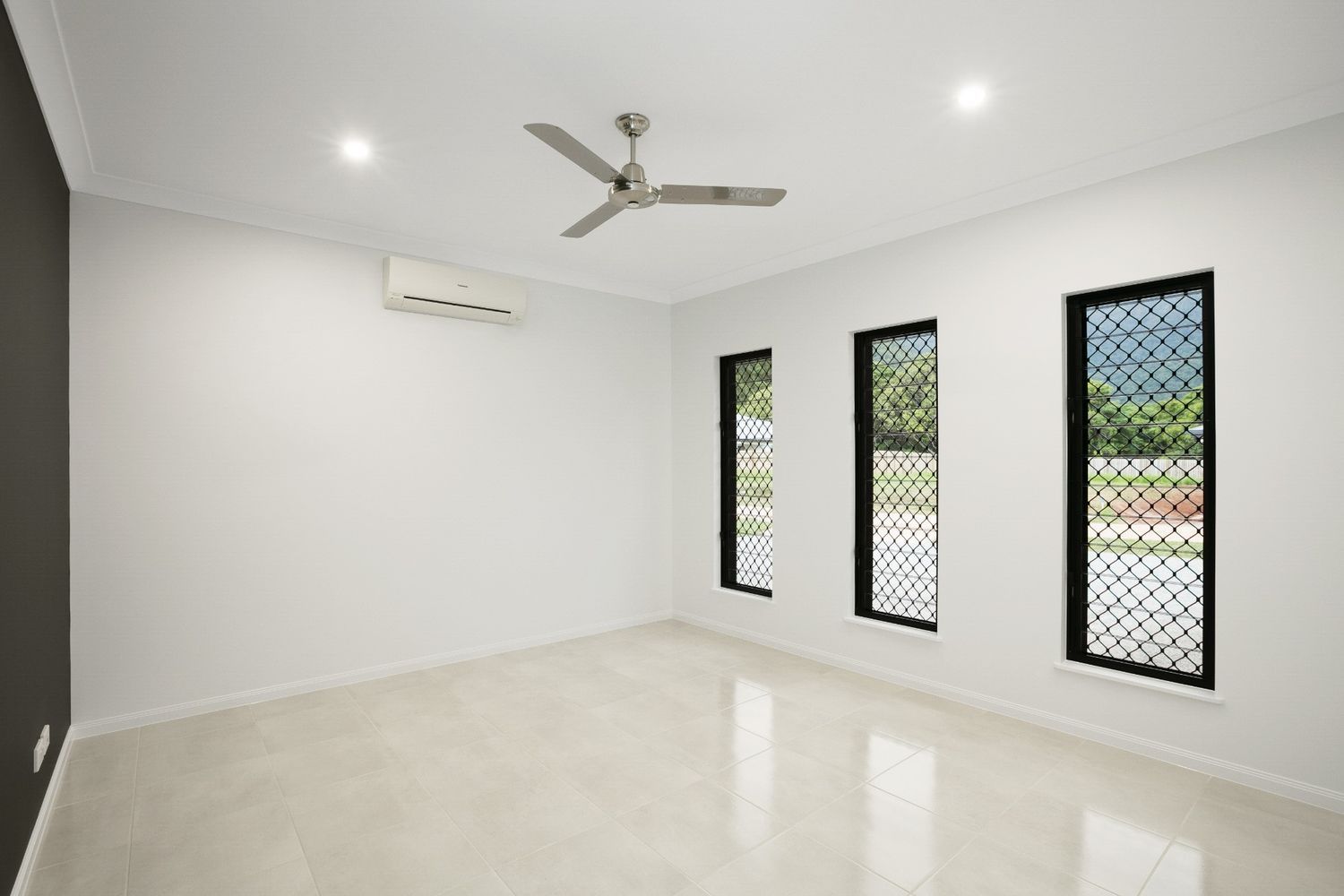 An Empty Room With Three Windows and a Ceiling Fan — Ashlee Jones Homes in Gordonvale, QLD