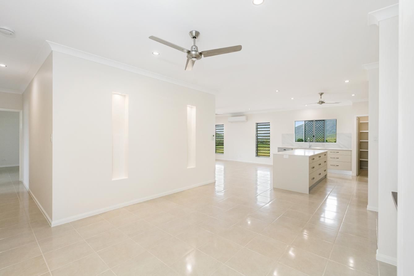 An Empty Living Room With a Ceiling Fan and a Kitchen — Ashlee Jones Homes in Gordonvale, QLD