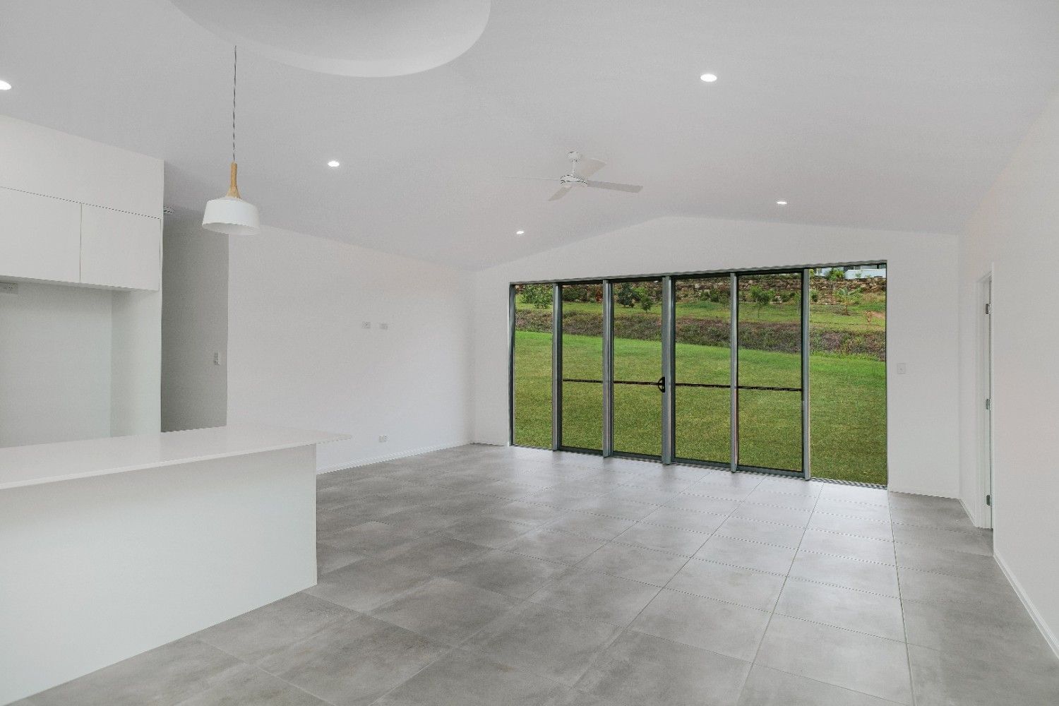 A Large Empty Room With a Lot of Windows and Sliding Glass Doors — Ashlee Jones Homes in Gordonvale, QLD