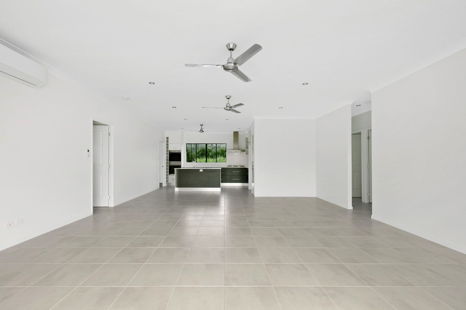 A Large Empty Room With Tile Floors and a Ceiling Fan — Ashlee Jones Homes in Gordonvale, QLD