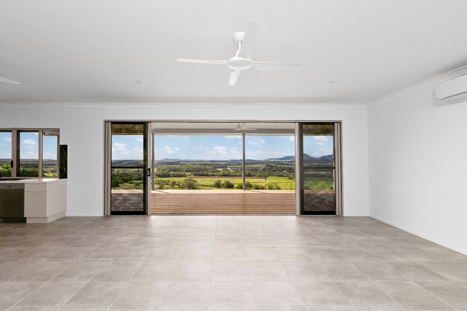 An Empty Living Room With a Ceiling Fan and Sliding Glass Doors — Ashlee Jones Homes in Gordonvale, QLD