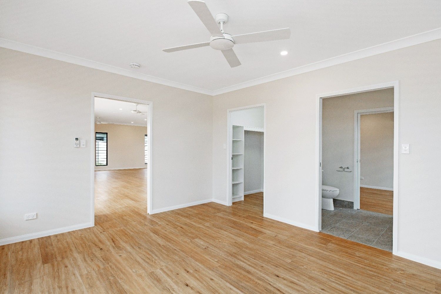 An Empty Living Room With Hardwood Floors and a Ceiling Fan — Ashlee Jones Homes in Gordonvale, QLD