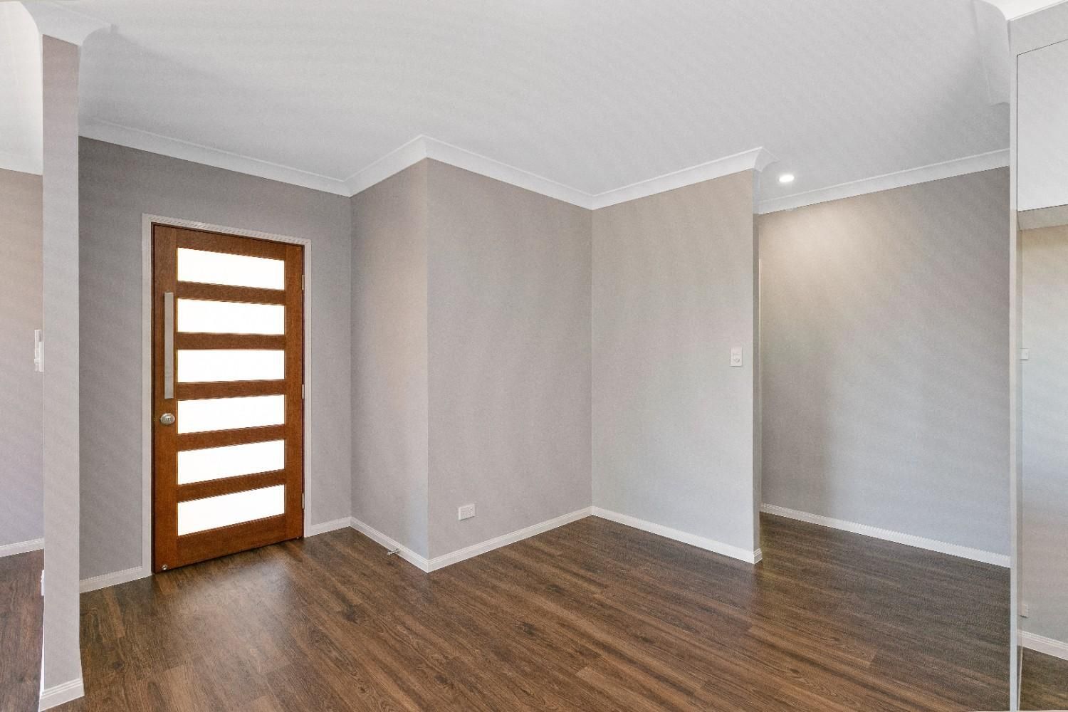 An Empty Living Room With Hardwood Floors and a Door — Ashlee Jones Homes in Gordonvale, QLD