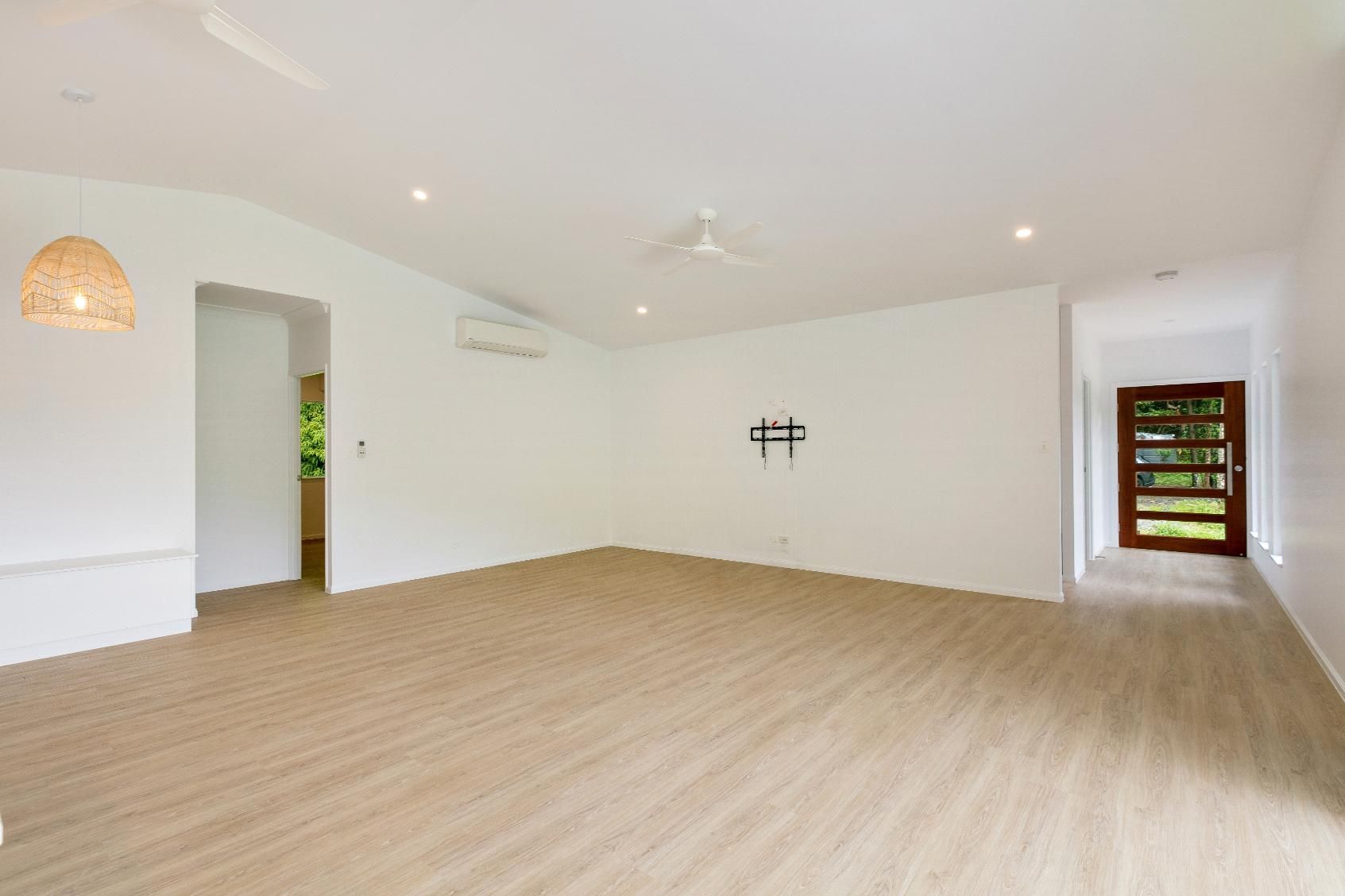 An Empty Living Room With a Wooden Floor and White Walls — Ashlee Jones Homes in Gordonvale, QLD