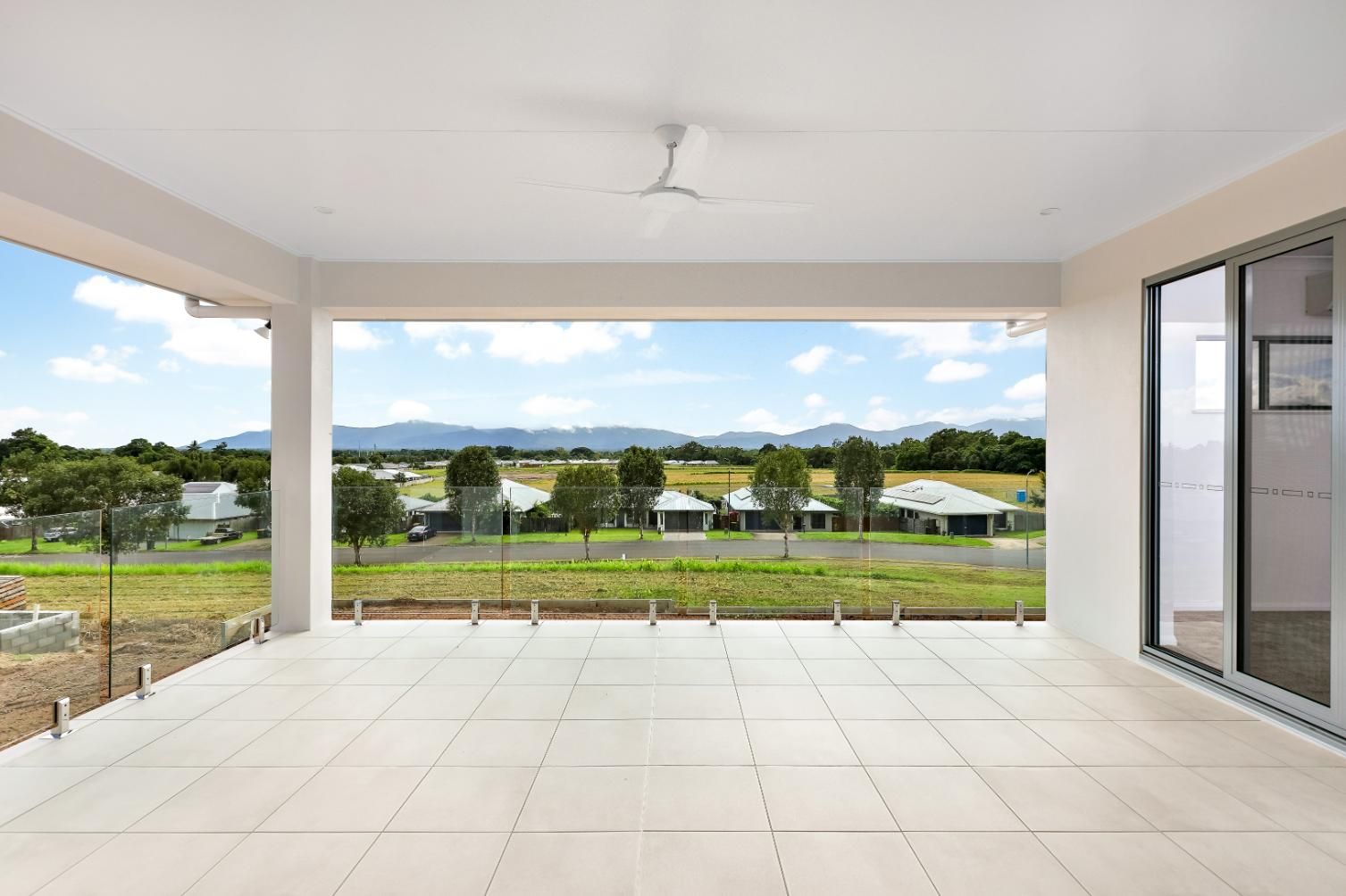 A Patio With a View of a Residential Area and a Ceiling Fan — Ashlee Jones Homes in Gordonvale, QLD