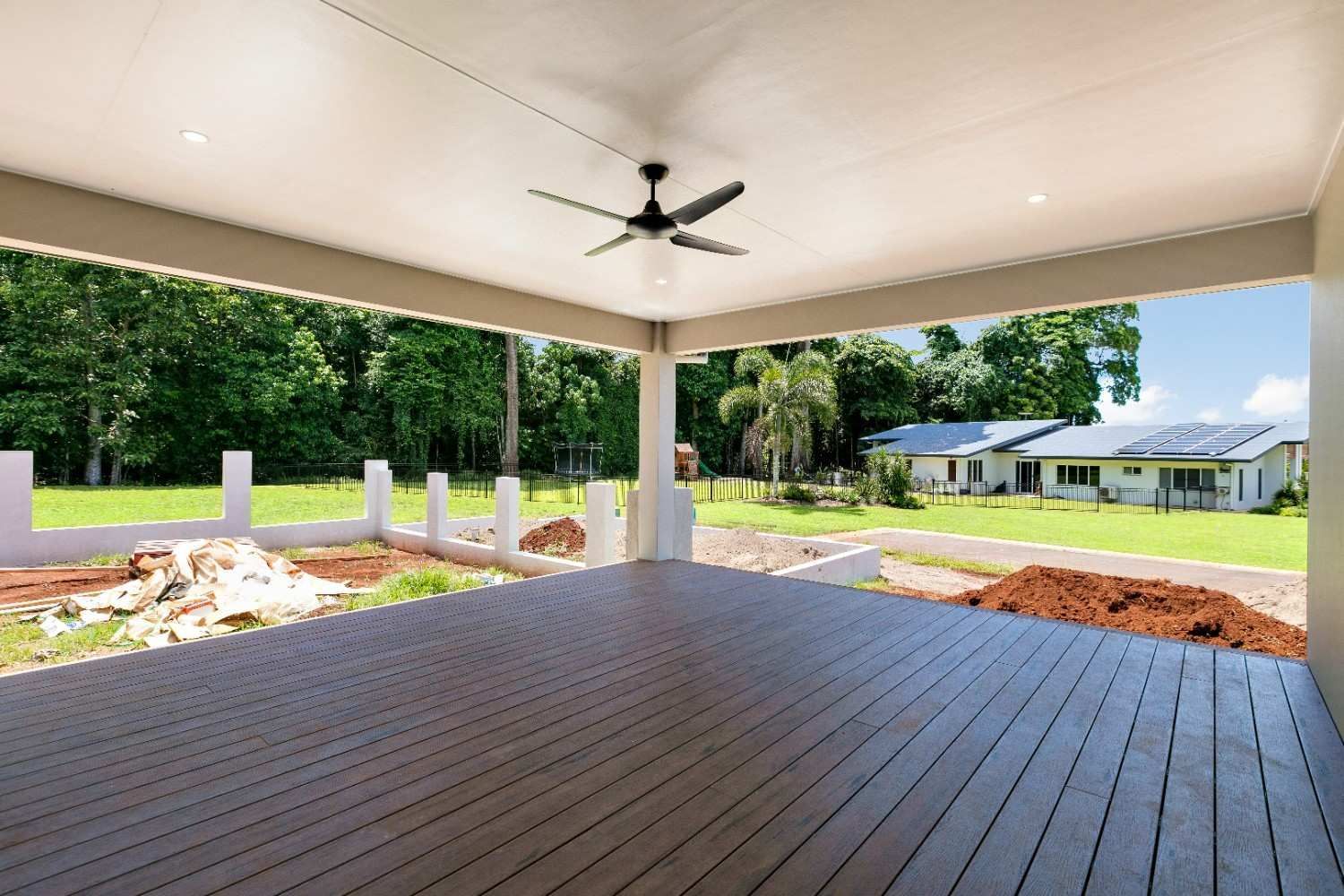 An Empty Deck With a Ceiling Fan and a View of a House in the Background — Ashlee Jones Homes in Gordonvale, QLD