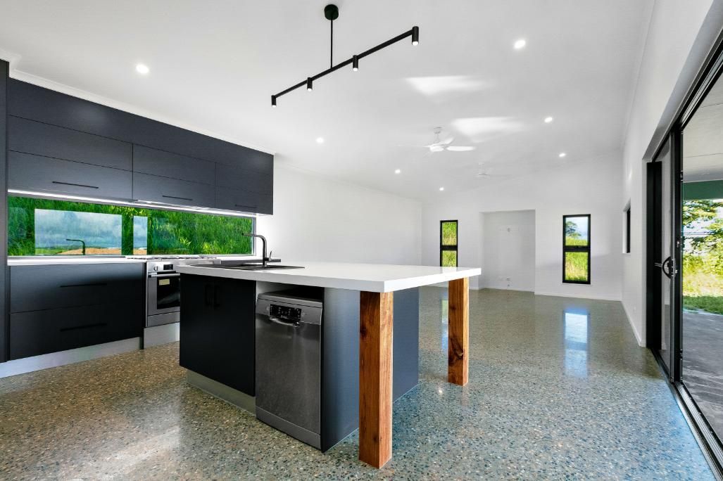An Empty Kitchen With a Large Island and Stainless Steel Appliances — Ashlee Jones Homes in Gordonvale, QLD