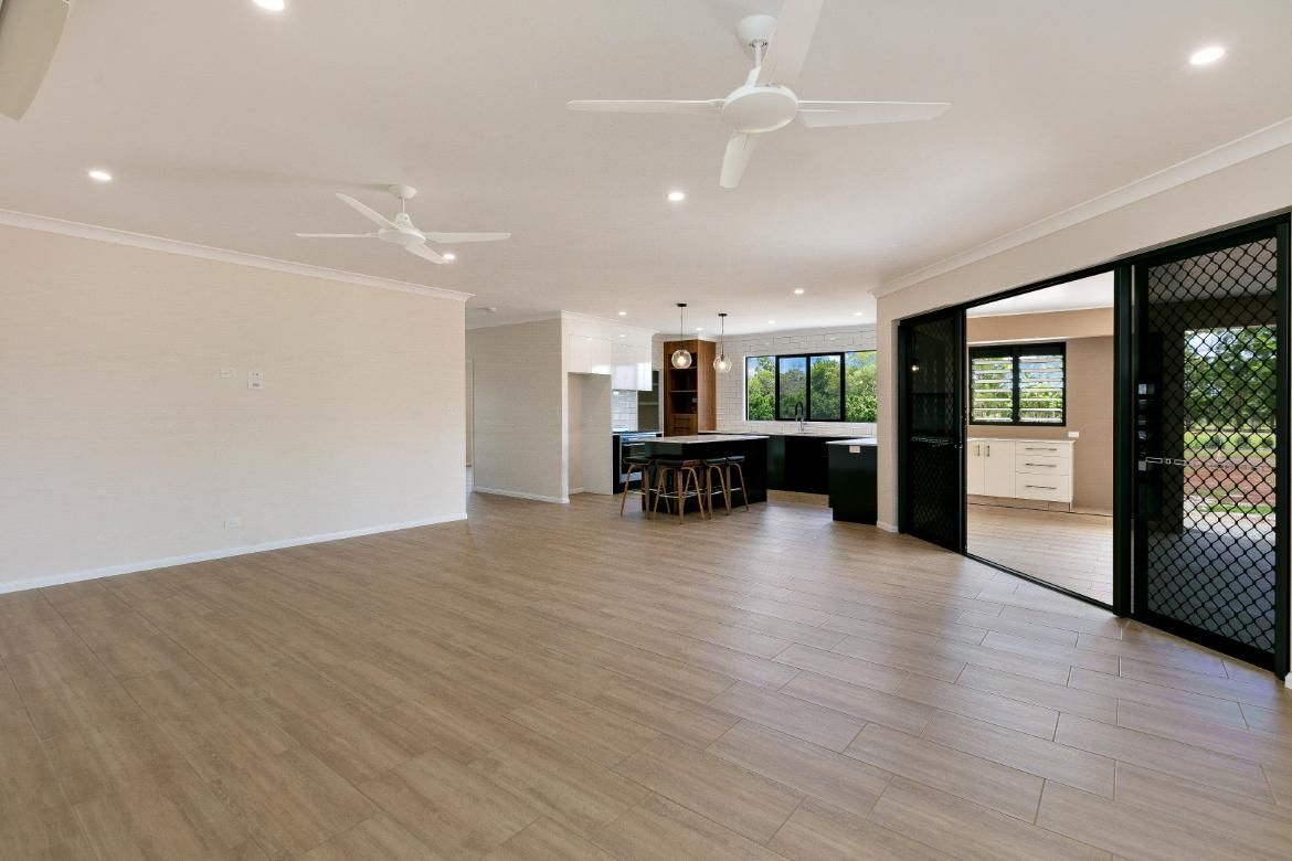 A Large Empty Room With Hardwood Floors and a Ceiling Fan — Ashlee Jones Homes in Gordonvale, QLD