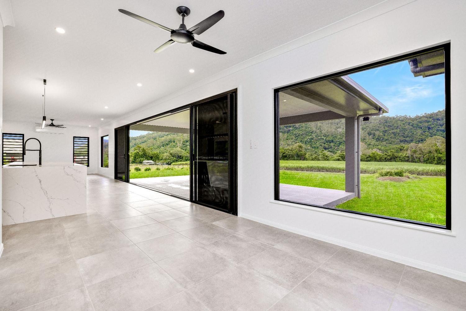 A Large Empty Room With a Ceiling Fan and a Lot of Windows — Ashlee Jones Homes in Gordonvale, QLD