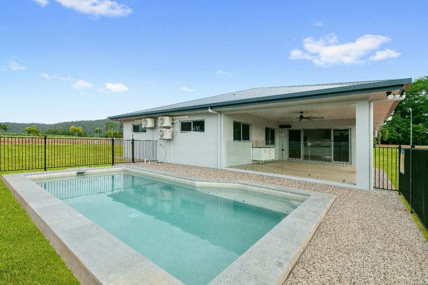 A House With a Large Swimming Pool in Front of It — Ashlee Jones Homes in Gordonvale, QLD