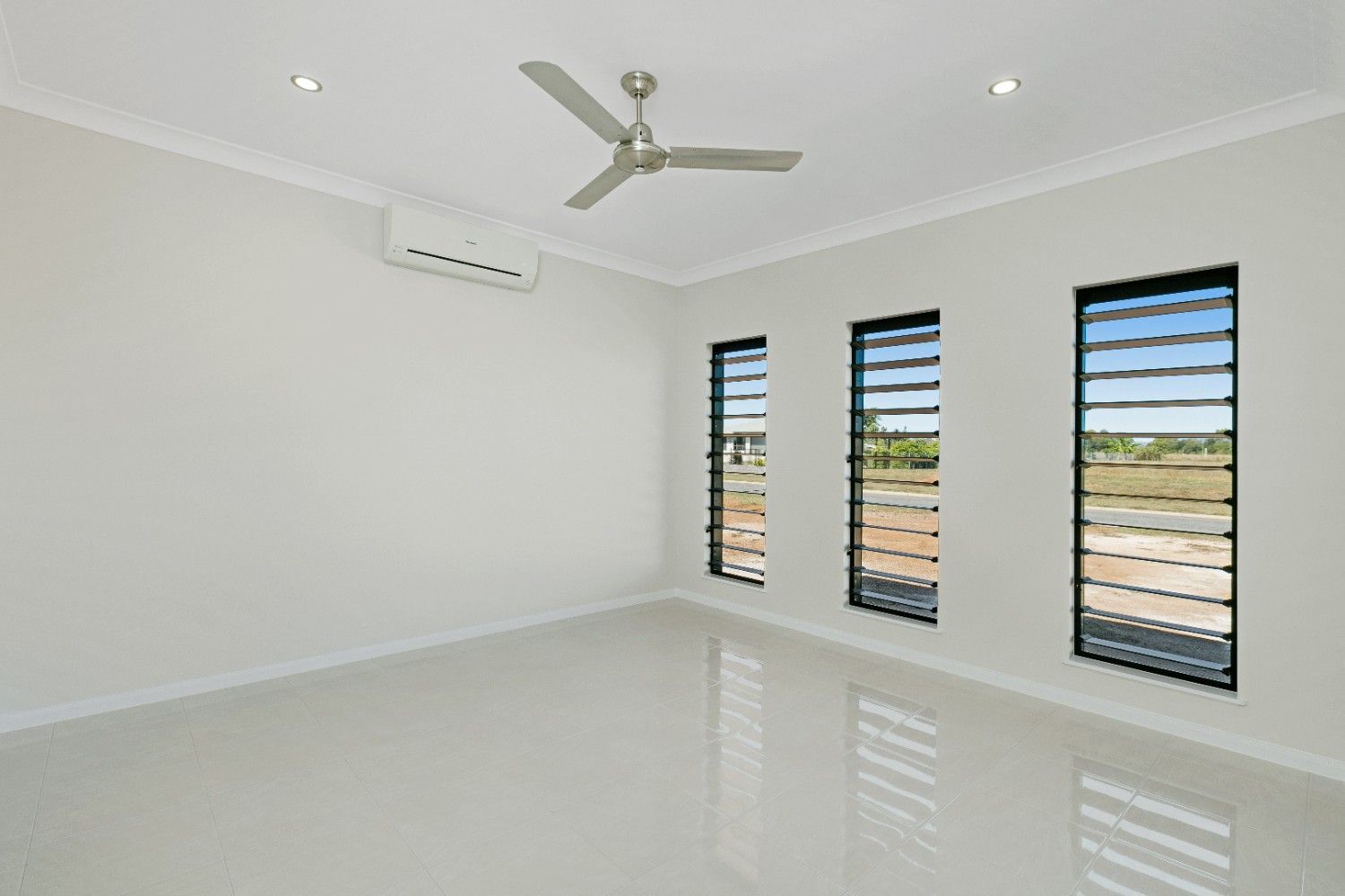 An Empty Room With a Ceiling Fan and Three Windows — Ashlee Jones Homes in Gordonvale, QLD