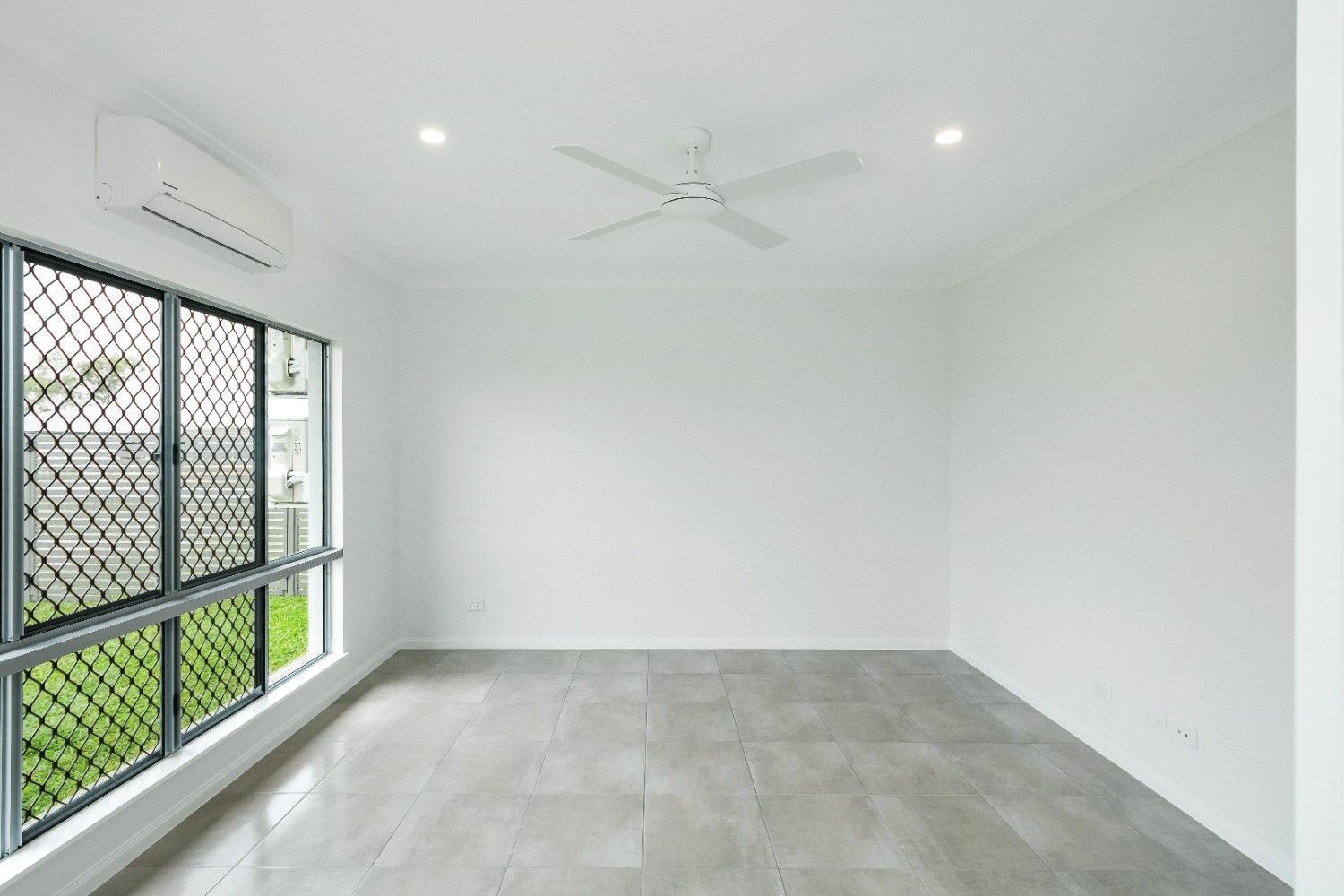 An Empty Room With a Ceiling Fan and Two Windows — Ashlee Jones Homes in Gordonvale, QLD