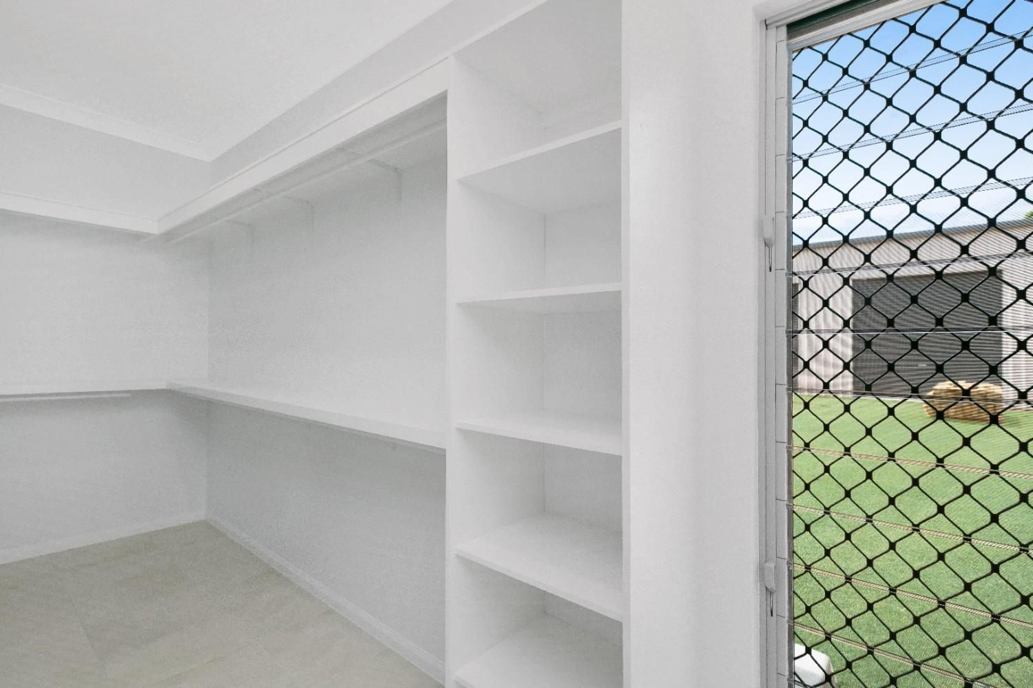 A Walk in Closet With Shelves and a Fence Behind It — Ashlee Jones Homes in Gordonvale, QLD