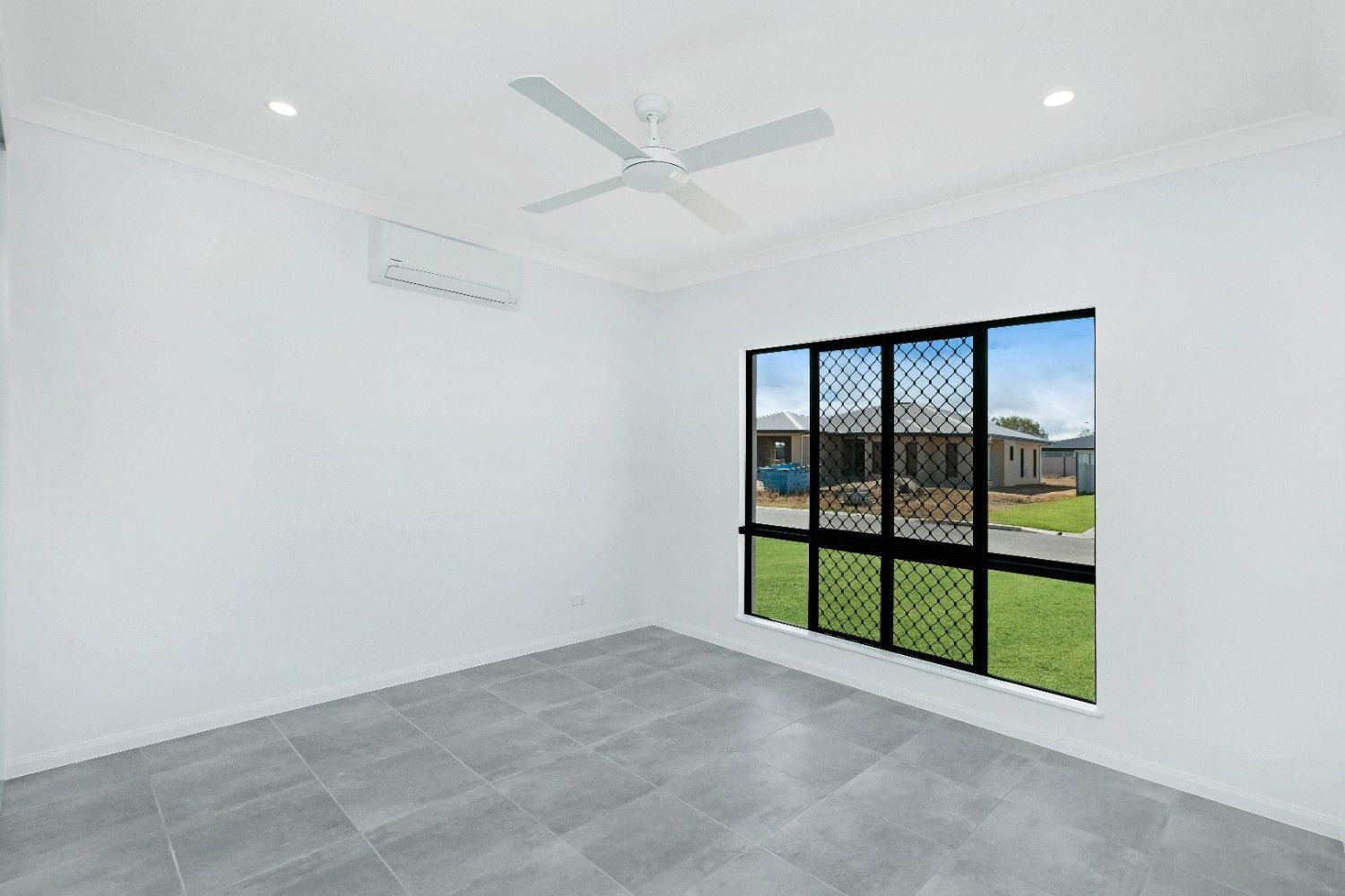 An Empty Room With a Ceiling Fan and Two Windows — Ashlee Jones Homes in Gordonvale, QLD