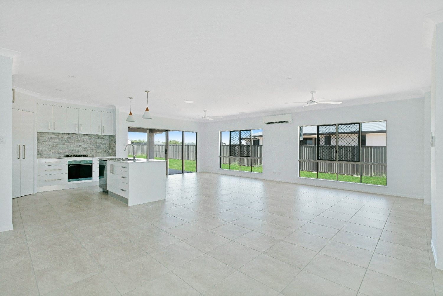 A Large Empty Room With a Kitchen and a Lot of Windows — Ashlee Jones Homes in Gordonvale, QLD