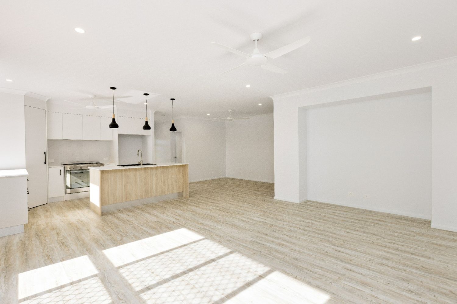 A Large Empty Room With a Kitchen and a Ceiling Fan — Ashlee Jones Homes in Gordonvale, QLD