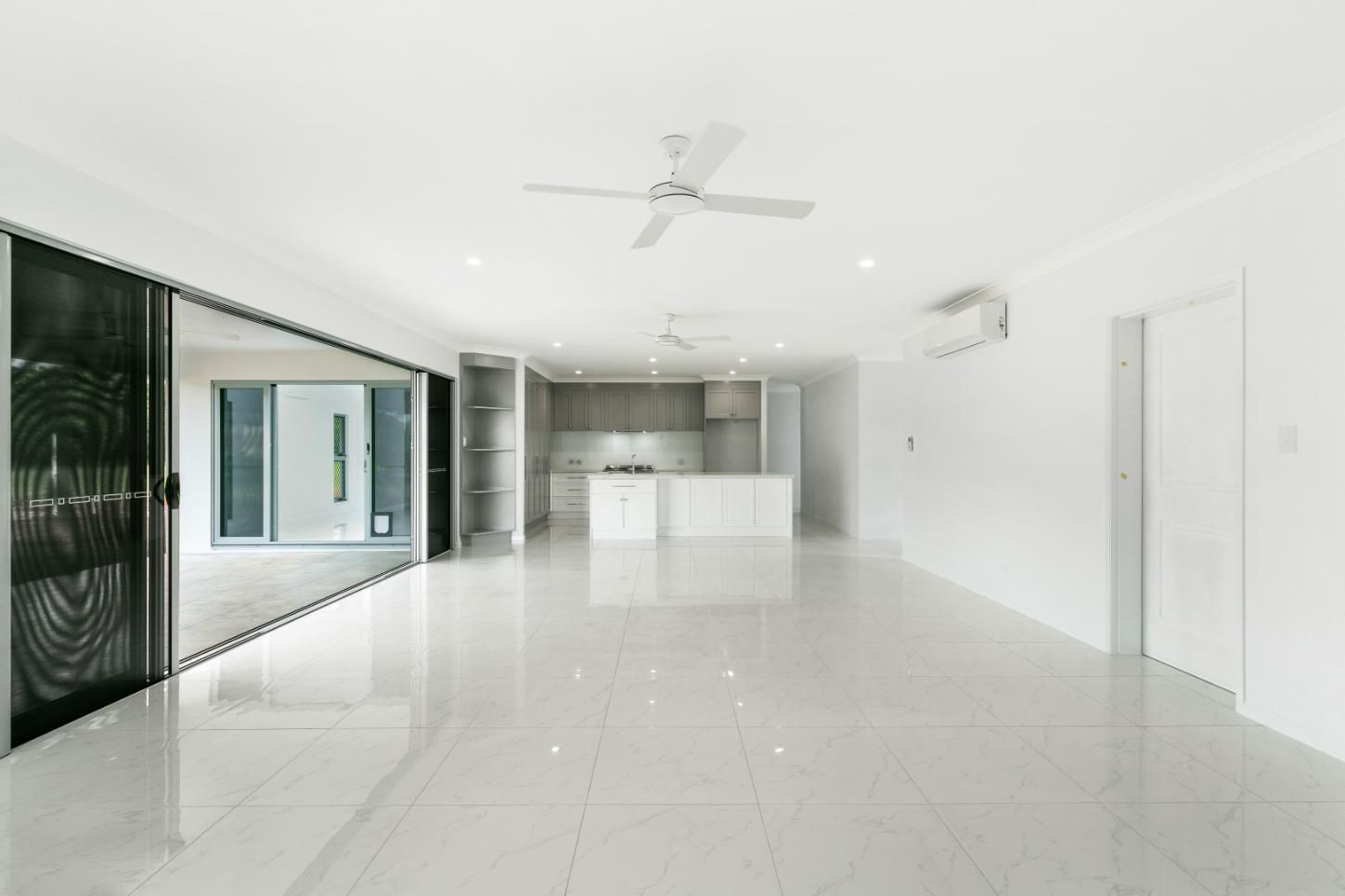 A Large Empty Room With a Ceiling Fan and a Kitchen — Ashlee Jones Homes in Gordonvale, QLD