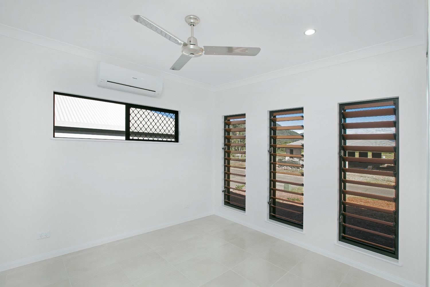An Empty Room With a Ceiling Fan and Three Windows — Ashlee Jones Homes in Gordonvale, QLD