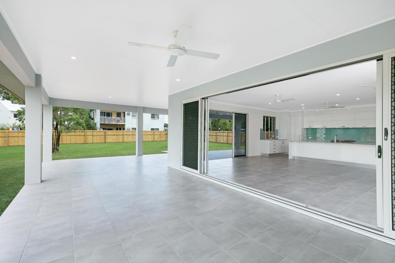 A Large Empty Room With Sliding Glass Doors and a Ceiling Fan — Ashlee Jones Homes in Gordonvale, QLD