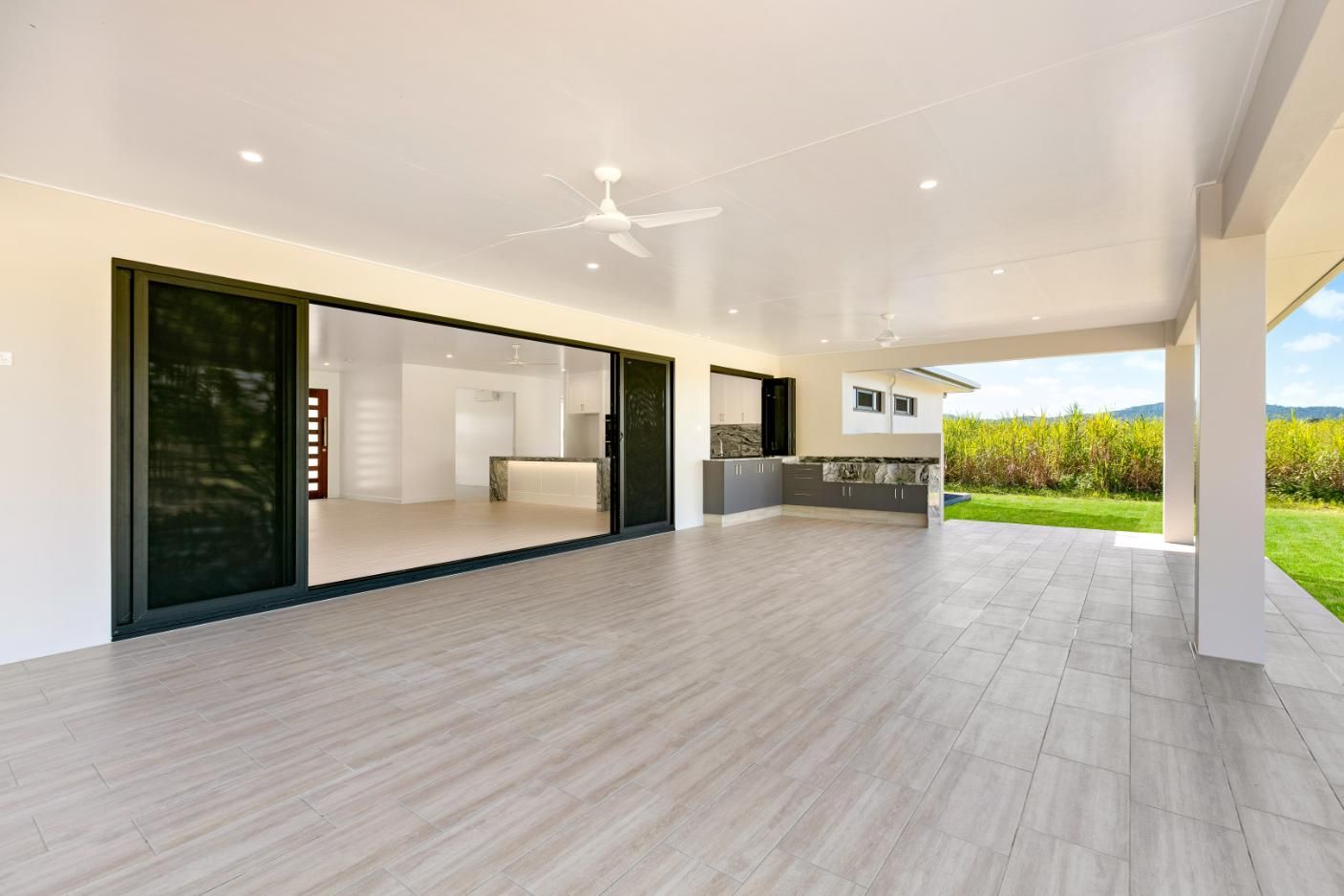 A Large Patio With Sliding Glass Doors and a Kitchen in the Background — Ashlee Jones Homes in Gordonvale, QLD
