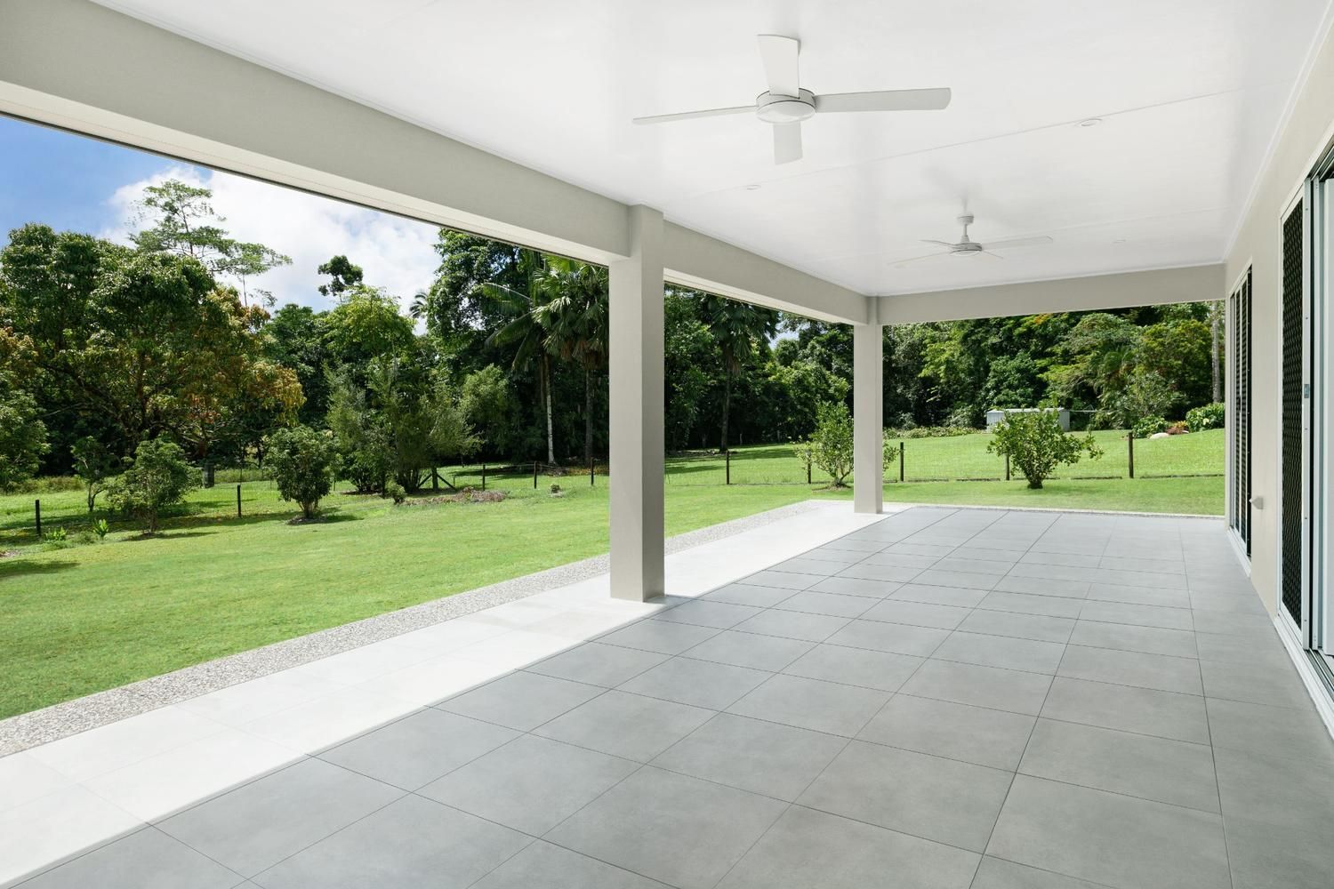 An Empty Porch With a Ceiling Fan and a View of a Lush Green Field — Ashlee Jones Homes in Gordonvale, QLD