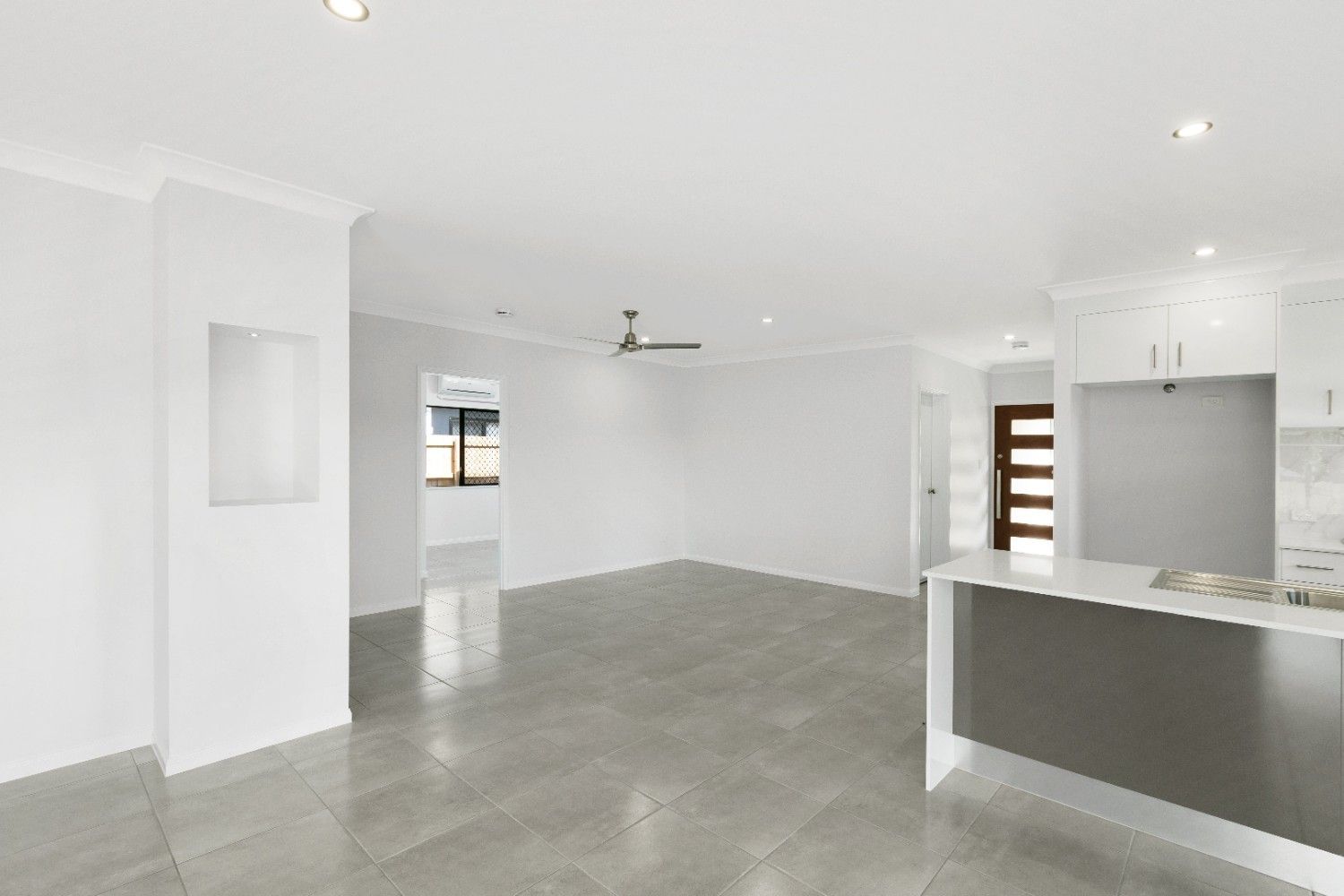 A Large Empty Room With a Kitchen and a Ceiling Fan — Ashlee Jones Homes in Gordonvale, QLD