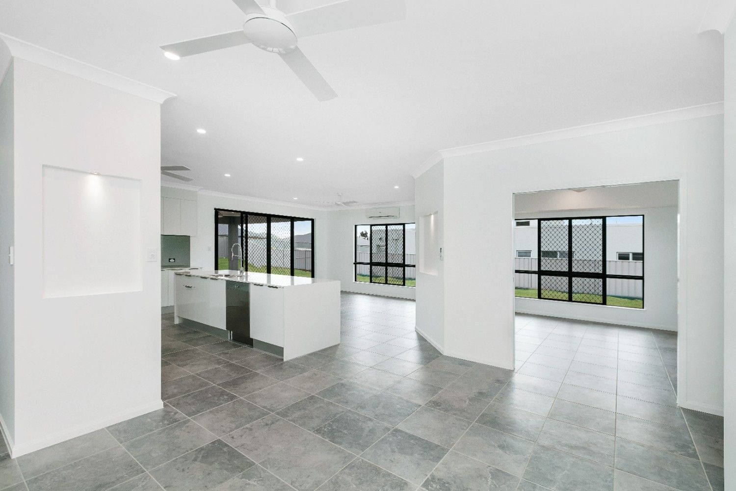 A Large Empty Room With a Ceiling Fan and a Tiled Floor — Ashlee Jones Homes in Gordonvale, QLD