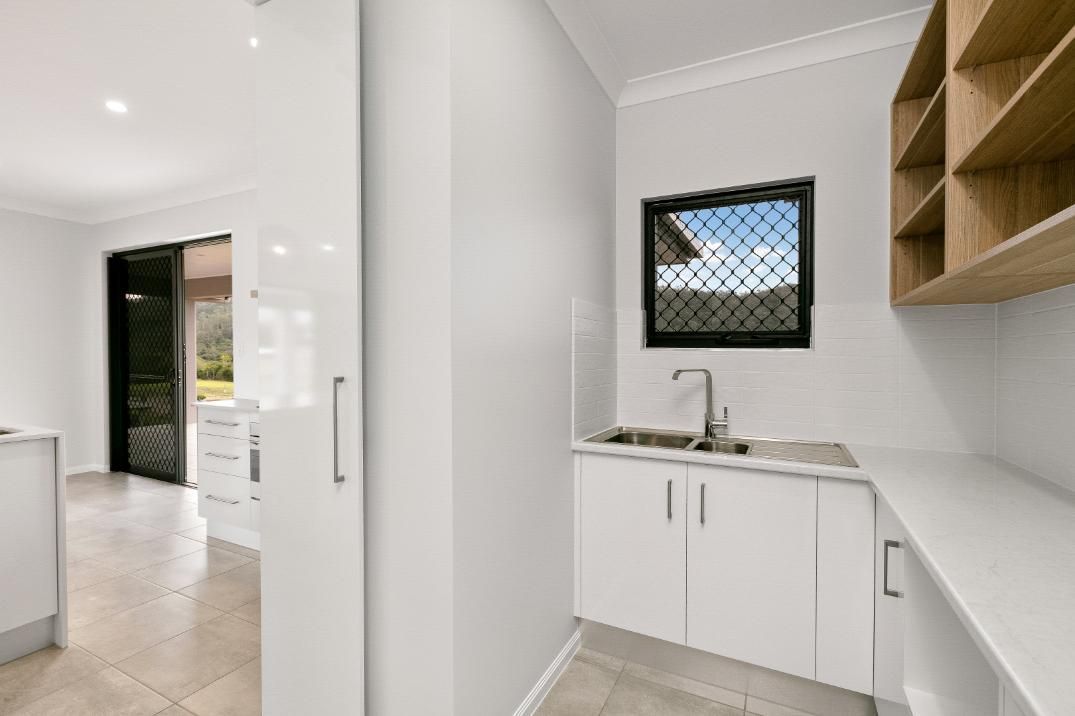 A Kitchen With White Cabinets, a Sink, and a Window — Ashlee Jones Homes in Gordonvale, QLD