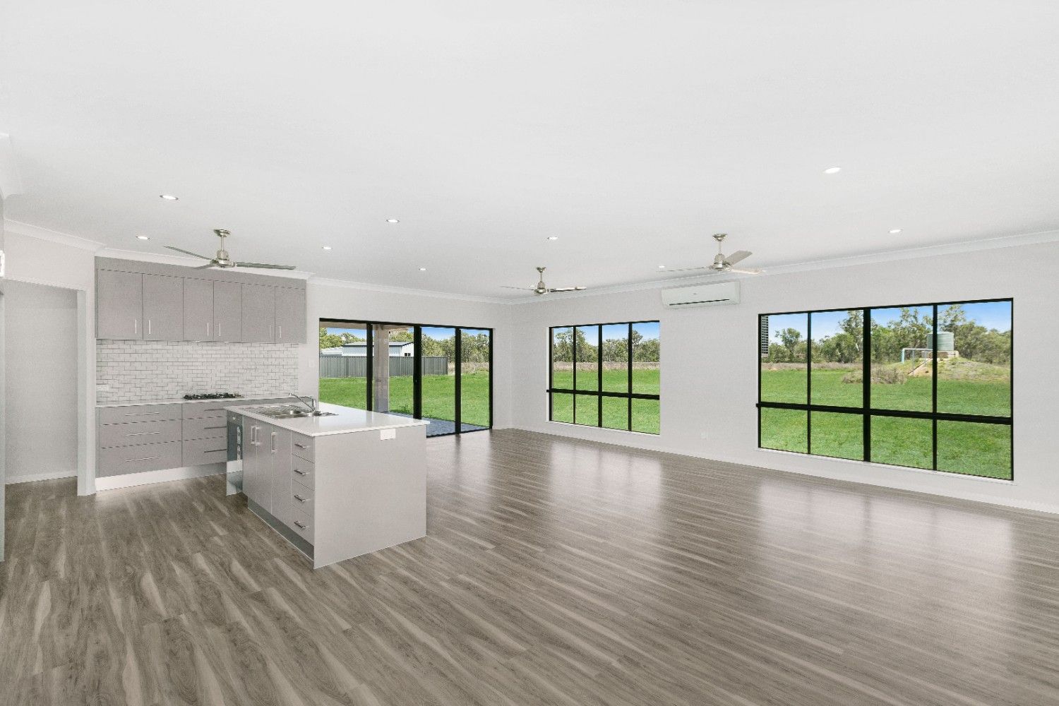A Large Empty Room With a Kitchen and a Lot of Windows — Ashlee Jones Homes in Gordonvale, QLD