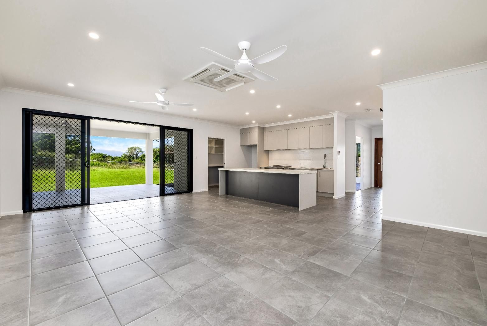 A Large Empty Room With a Kitchen and a Ceiling Fan — Ashlee Jones Homes in Gordonvale, QLD