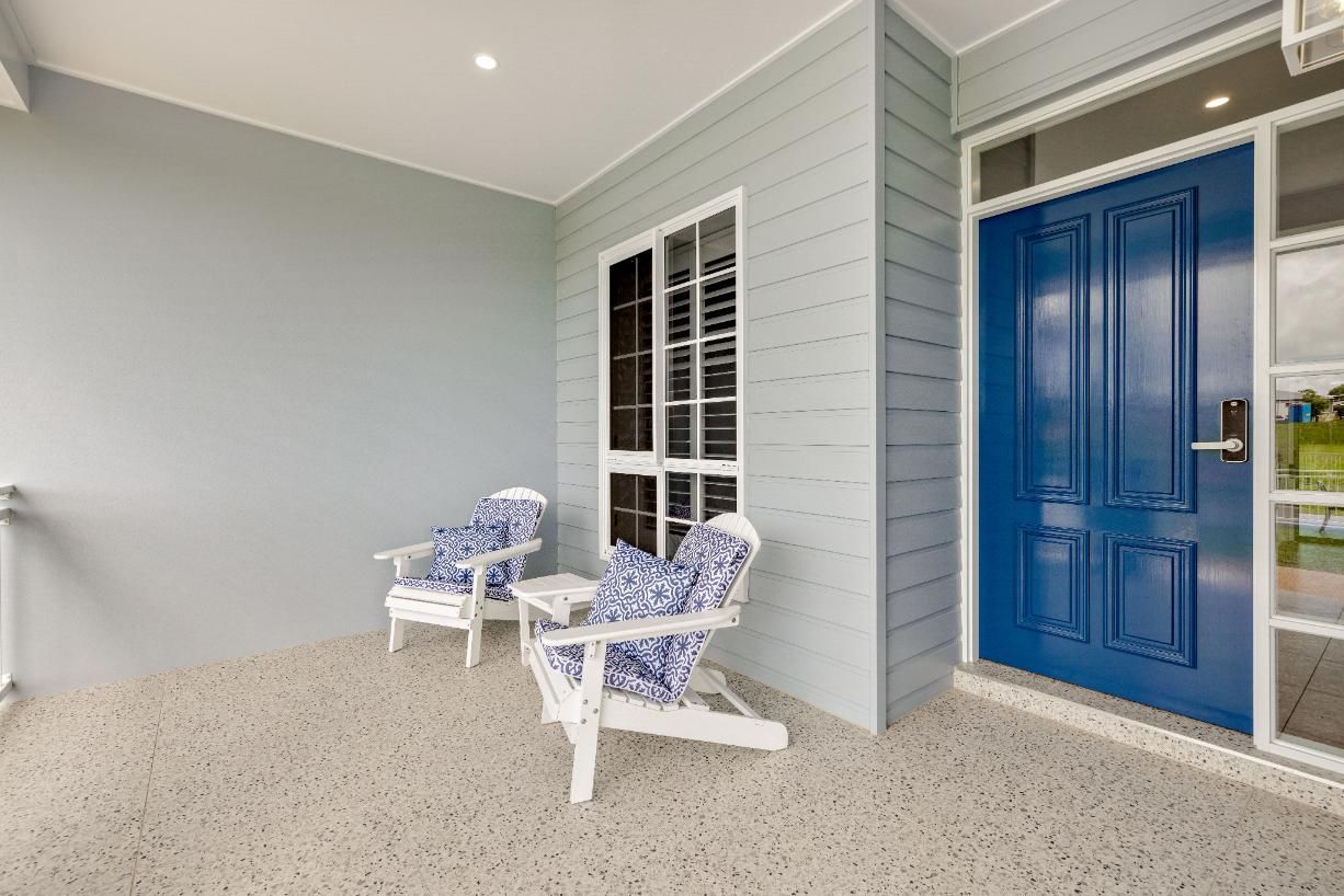 There Are Two Chairs on the Porch of a House With a Blue Door — Ashlee Jones Homes in Gordonvale, QLD