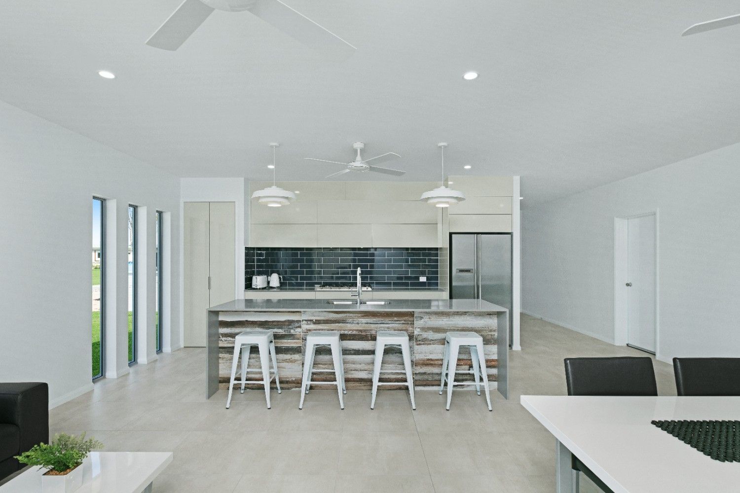 A Kitchen and Dining Room in a White House With a Ceiling Fan — Ashlee Jones Homes in Gordonvale, QLD
