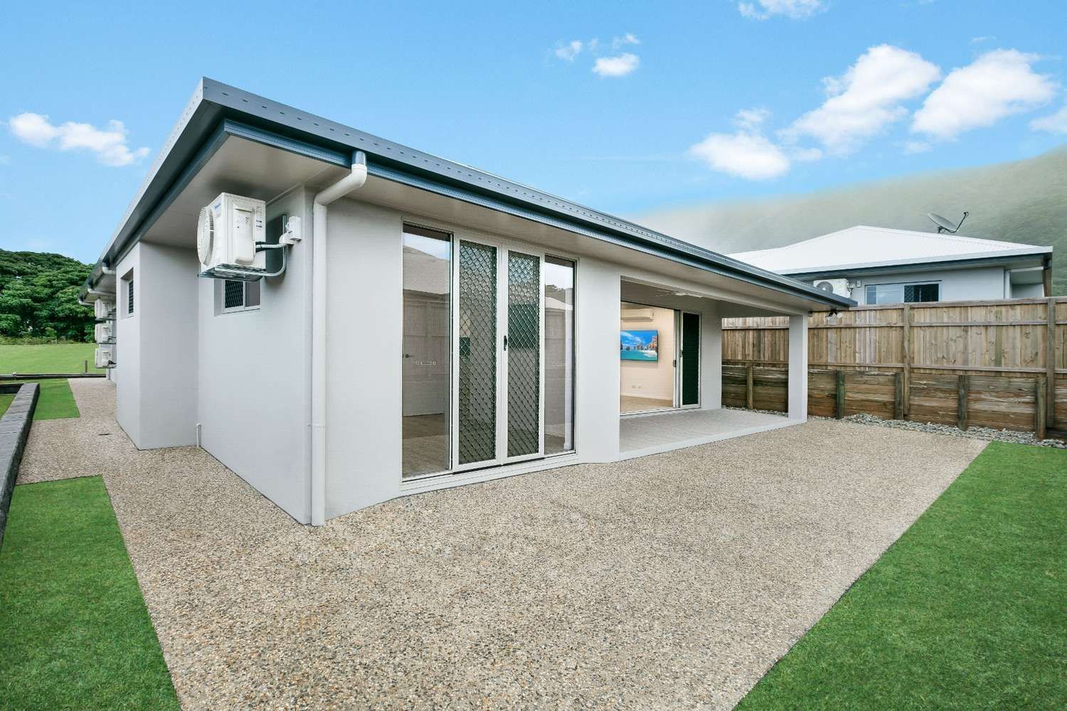 A White House With a Lot of Windows and a Gravel Driveway in Front of It — Ashlee Jones Homes in Gordonvale, QLD